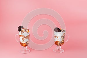 Sweet dessert in glass with biscuit and whipped cream on pink bsckground, selective focus and blank space