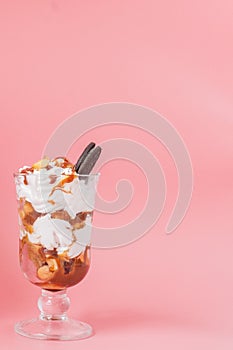 Sweet dessert in glass with biscuit and whipped cream on pink bsckground, selective focus and blank space