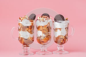 Sweet dessert in glass with biscuit and whipped cream on pink bsckground, selective focus and blank space