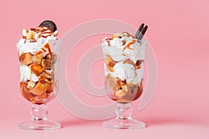 Sweet dessert in glass with biscuit and whipped cream on pink bsckground, selective focus and blank space