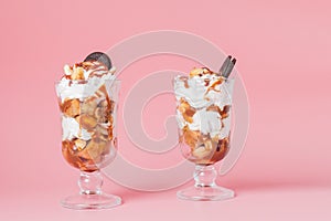 Sweet dessert in glass with biscuit and whipped cream on pink bsckground, selective focus and blank space
