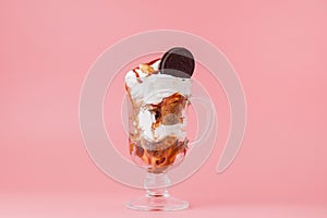 Sweet dessert in glass with biscuit and whipped cream on pink bsckground, selective focus and blank space