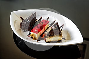 Sweet dessert of pieces of chocolate cakes and cheesecake with icing and fresh strawberry