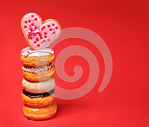 Sweet donuts with heart shaped donut on the top over red