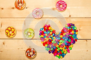 Sweet donuts with heart shaped on wooden background
