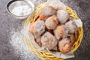 Sweet donuts oliebollen with raisins and powdered sugar close-up in a basket. Horizontal top view