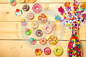 Sweet donuts pastel color with rose flower on wooden background