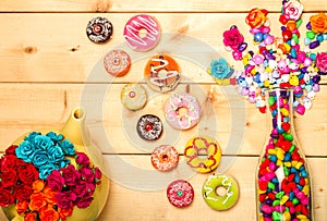 Sweet donuts pastel color with rose flower on wooden background