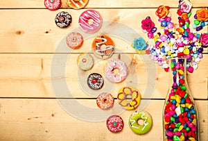 Sweet donuts pastel color with rose flower on wooden background