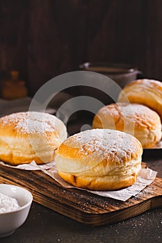 Sweet donuts with powdered sugar filled with boiled condensed milk on a plate vertical view