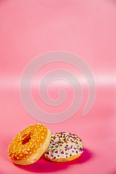 Sweet donuts stacked in a stack on a pink background. Copy space, various glaze and sprinkels chocolate chip, snack fast