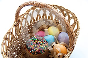 Sweet Easter cake with colorful eggs in a wicker basket isolated on white background