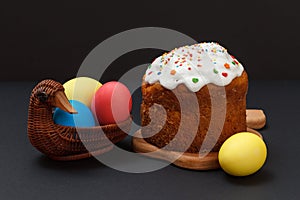 Easter cake and colorful Easter eggs in wicker basket