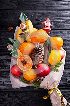 Sweet eatable bouquet made of fruits wrapped in paper on black background