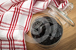 Sweet food and edible confectionary concept with top view of a jar with many wheels of black licorice in a rustic setting