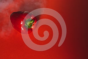 SWEET, fresh RED PEPPER ON A RED BACKGROUND WITH A LIGHT SMOKE.