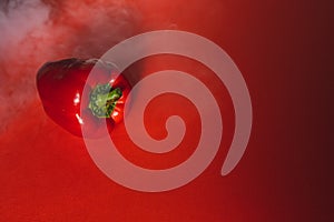 SWEET, fresh RED PEPPER ON A RED BACKGROUND WITH A LIGHT SMOKE.