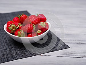 Sweet fresh strawberries in bowl on a wooden table. Food concept. photo