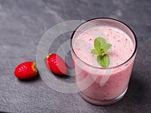 Sweet fresh strawberries jogurt in a glass on a gray background. Food concept.