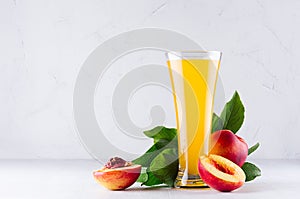 Sweet fresh yellow juice of peach and red nectarines with green leaves, juicy half cut on white wood table.