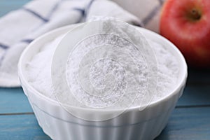 Sweet fructose powder and apple on light blue wooden table, closeup