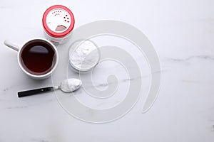 Sweet fructose powder and cup of tea on white marble table, flat lay. Space for text