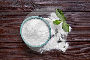 Sweet fructose powder and mint leaves on dark wooden table, flat lay