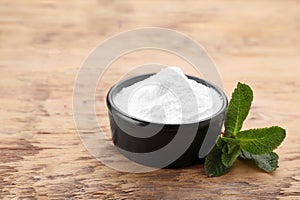 Sweet fructose powder and mint leaves on wooden table