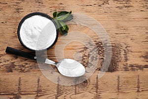 Sweet fructose powder and mint leaves on wooden table, flat lay. Space for text