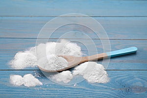 Sweet fructose powder and spoon on light blue wooden table