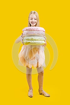 Sweet gift. Round dessert. Christmas sweetness. A cute girl is holding two huge macaroons on a yellow background