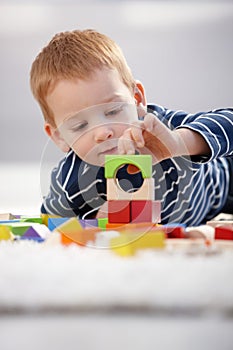 Sweet gingerish boy building tower at home