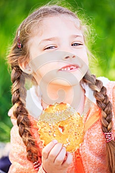 Sweet girl with a fallen tooth holding a cookies in her hand