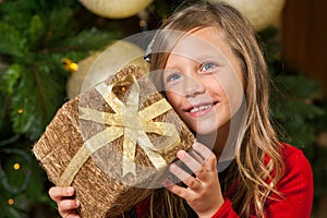 Sweet girl holding present at christmas tree.