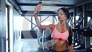 The sweet girl is making selfie on the background of the gym