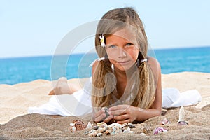 Sweet girl playing with shells on beach.