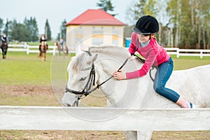 A sweet girl riding a white horse, an athlete engaged in equestrian sports, a girl hugs and kisses a horse.