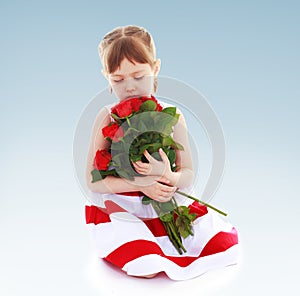 Sweet girl smelling a bouquet of red roses.