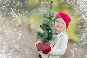 Sweet Girl Wearing Mittens Holding Small Christmas Tree with Snow Effe