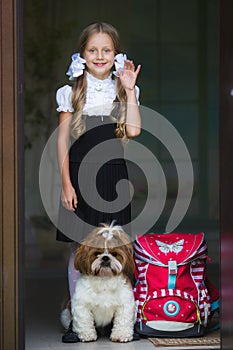 Sweet girl with white bows in a school uniform with a cute little dog.