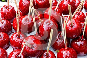 Sweet glazed red toffee candy apples on sticks for sale on farmer market or country fair