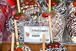 Sweet glazed red toffee candy apples on sticks for sale on farmer market or country fair