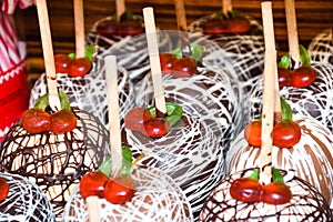 Sweet glazed red toffee candy apples on sticks for sale on farmer market or country fair