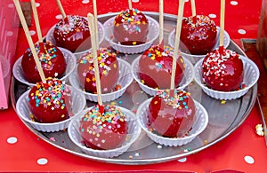 Sweet glazed red toffee candy apples on sticks for sale on farmer market or country fair. Thanksgiving and Halloween homemade red
