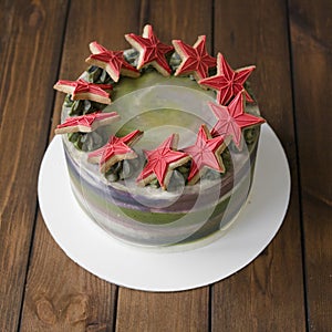 Sweet green-gray cake with decor on 23 february holiday - Red stars cookies and number 23 - on wooden background. Close