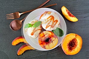 Sweet grilled peaches with vanilla ice cream and caramel sauce, top view table scene on slate photo