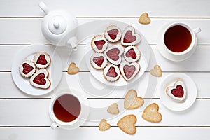 Sweet heart cookies for Valentines day with teapot and two cups of tea composition on white wooden background