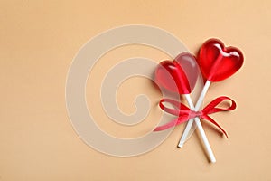 Sweet heart shaped lollipops on beige background, top view with space for text. Valentine`s day celebration