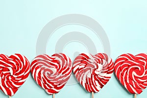 Sweet heart shaped lollipops on light blue background, flat lay with space for text. Valentine`s day celebration