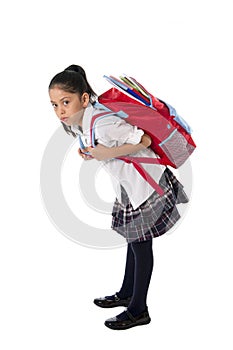 Sweet hispanic little school girl carrying very heavy backpack or schoolbag full